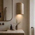 Nagisa wall light, a curved natural travertine shell beside a bathroom mirror